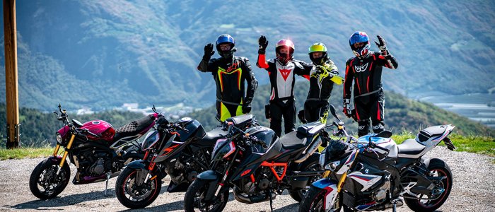 Vier Motorradfahrer mit ihren Motorrädern vor Bergkulisse