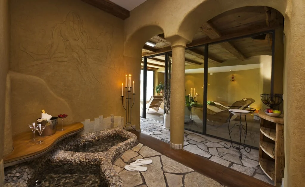 Entspannungsbereich mit Steinbadewanne, Kerzen und Loungestühlen im Hintergrund