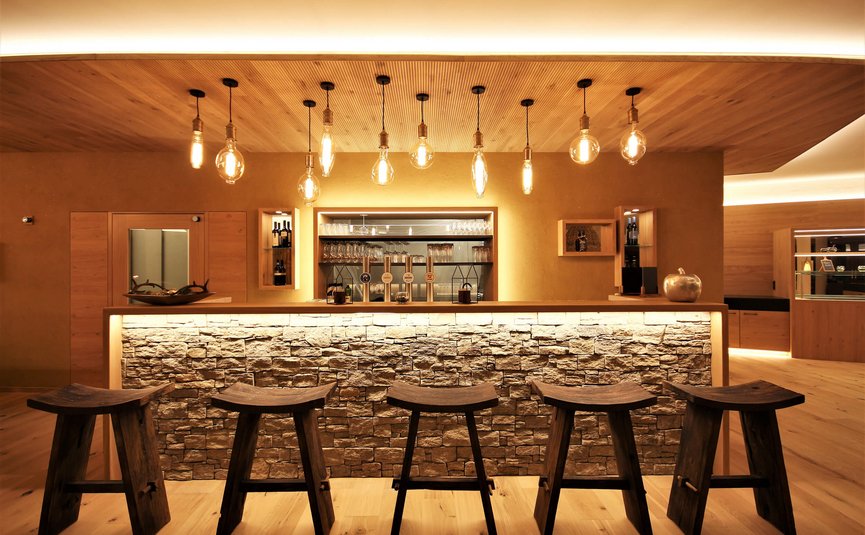 Moderner Barbereich mit Holzstühlen und beleuchteter Steintheke