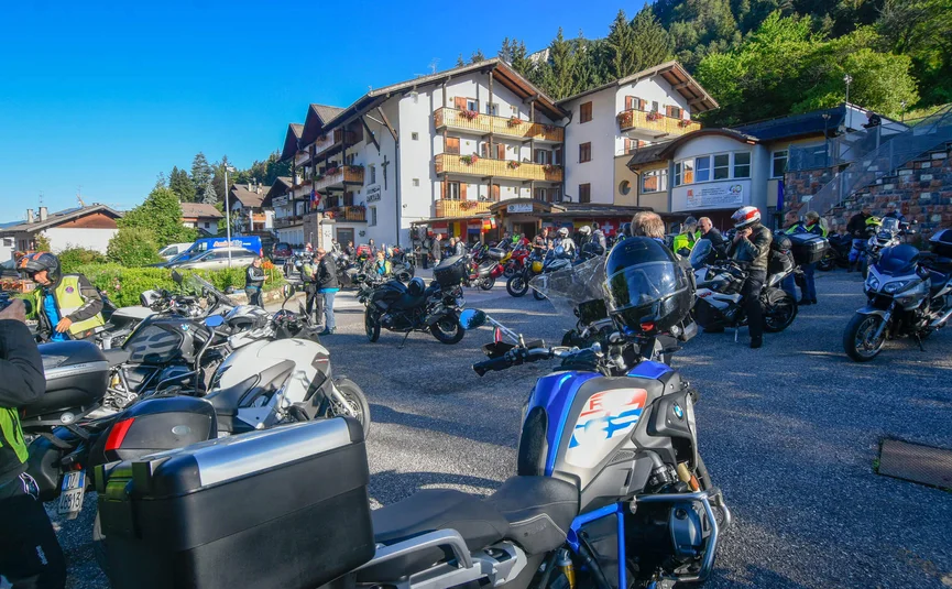 Motorrijders verzamelen zich bij een berghut op een zonnige dag