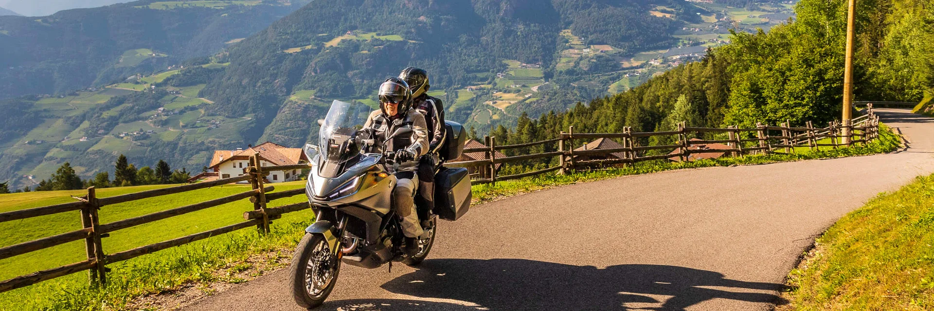 Two motorcyclists riding on mountain road with green valleys and hills
