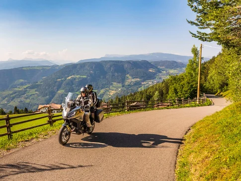 Zwei Motorradfahrer auf Bergstraße mit Blick auf grüne Täler und Berge