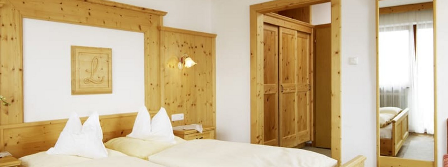 Firns Snow Weekpackage Bright bedroom with wooden furniture, double bed, and large mirror