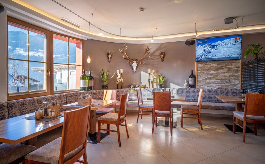 Hell eingerichtetes Restaurant mit Holztischen und Hirschgeweih an der Wand