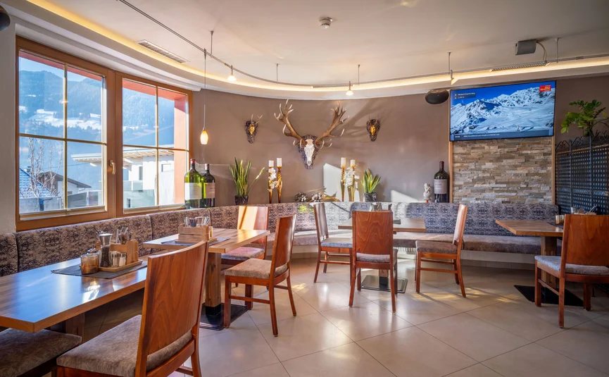 Bright restaurant interior with wooden tables and deer antlers on wall