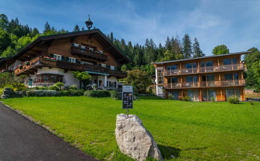 2 Center Tour Grossglockner Traditionelles Holzhaus und modernes Gebäude auf grünem Hügel vor Wald