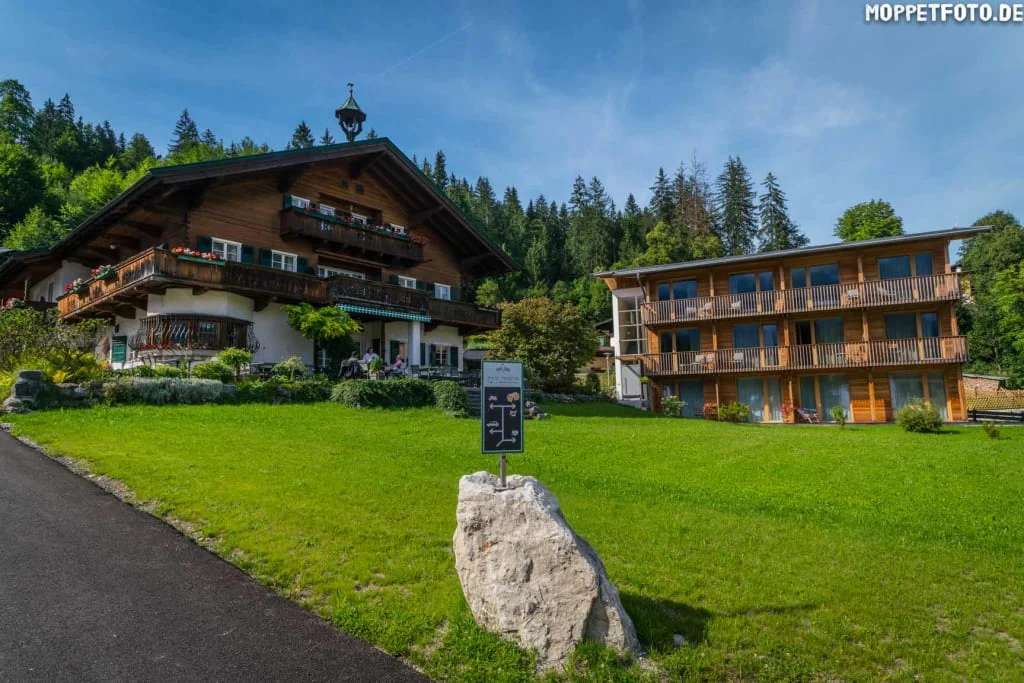 2 Center Tour Grossglockner Traditionelles Holzhaus und modernes Gebäude auf grünem Hügel vor Wald