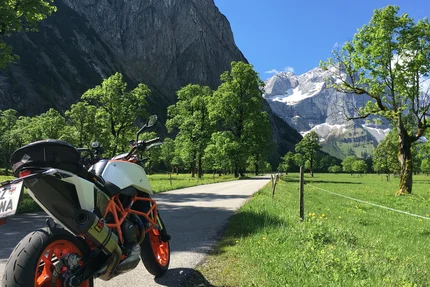 Motorcycle on road with mountains and green trees on a sunny day