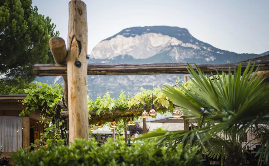 Outdoor dining area with wooden beams, hanging lights, and mountain backdrop