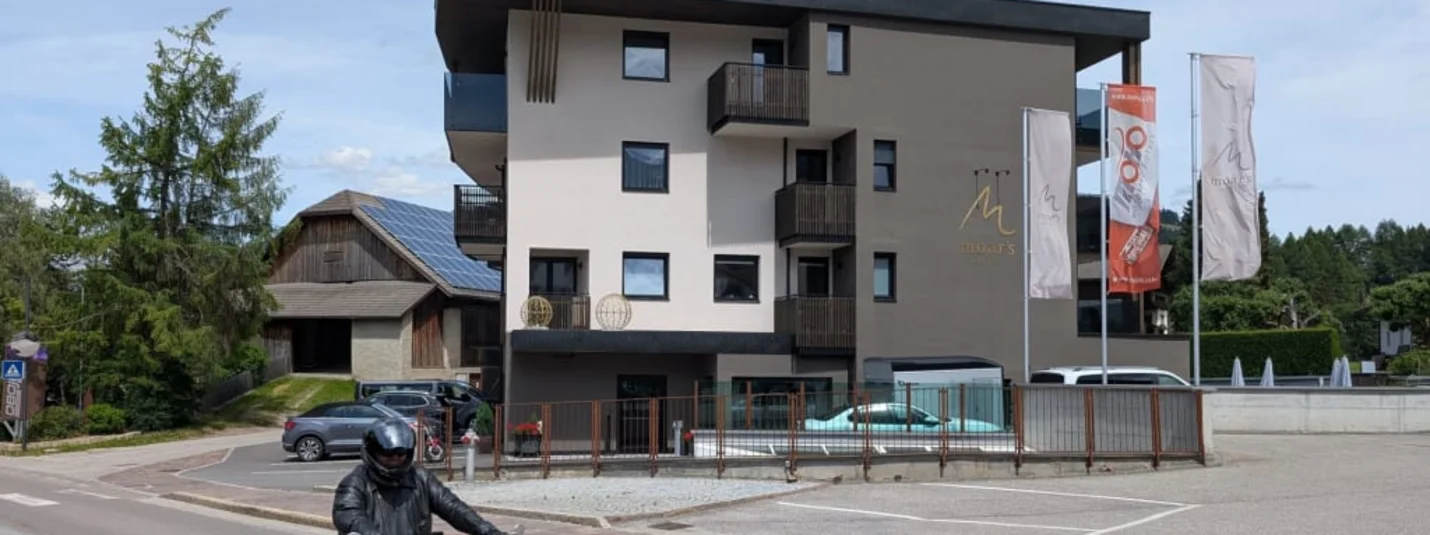 Moar's Bike & Relax Week Modern hotelgebouw met balkons en vlaggen langs de weg met motorrijder