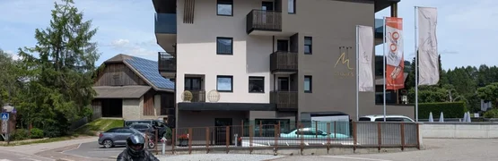 Moar's Bike & Relax Week Modern hotelgebouw met balkons en vlaggen langs de weg met motorrijder