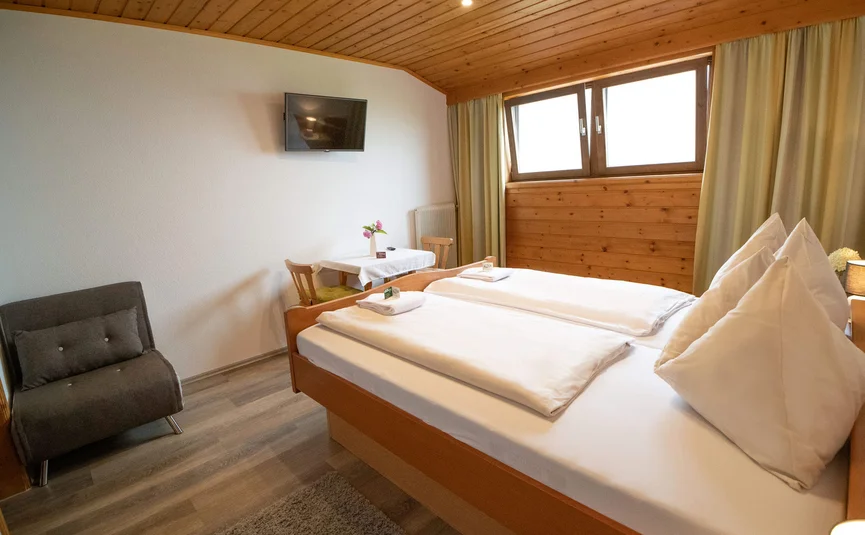 Cozy bedroom with double bed, TV, and small seating area