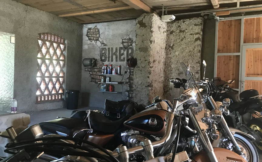 Motorcycles parked inside a garage with concrete walls and wooden ceiling