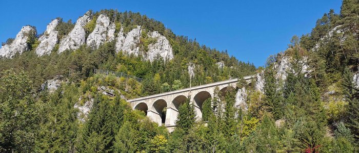 Steinbogenbrücke in bewaldeten Bergen unter blauem Himmel