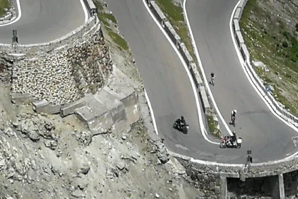 Hairpin turns on mountain road with motorcycles and cyclists