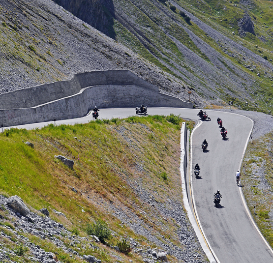 Motorradfahrer und Radfahrer auf kurvenreicher Bergstraße