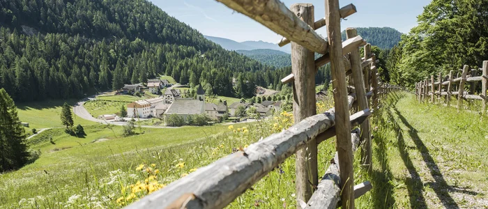 Houten hek langs pad met bergdorp en bos bij heldere lucht