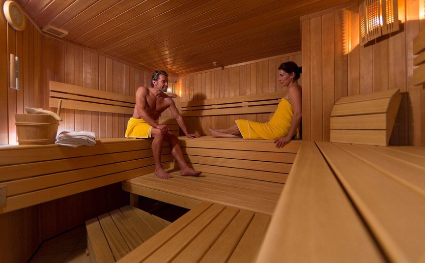 Mann und Frau entspannen in einer Sauna mit Holzverkleidung