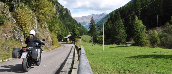 Motorcyclist riding on mountain road with forest and mountains in background