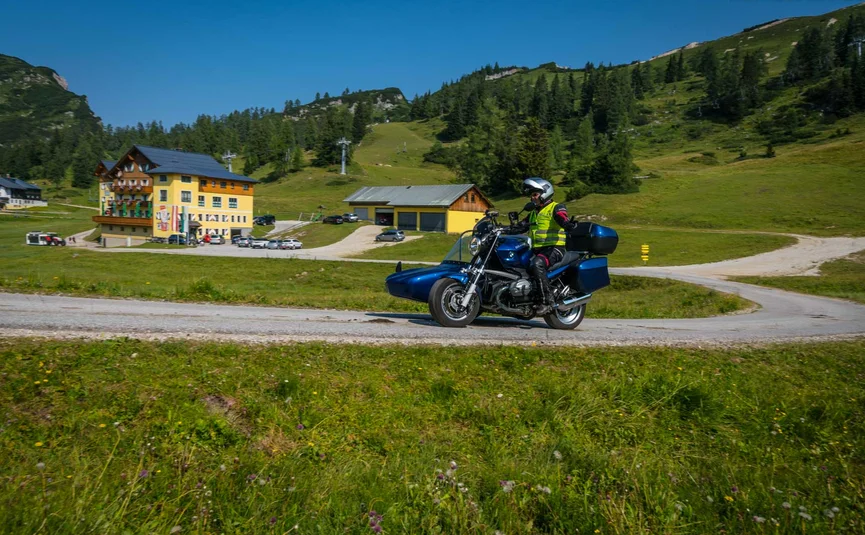 Motorcyclist with sidecar on country road near alpine hotel on sunny day