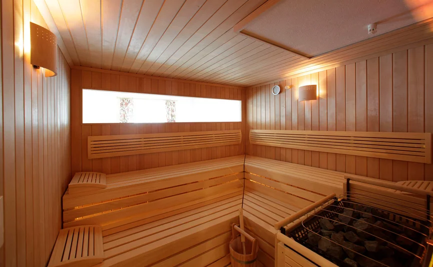 Hotel Rose **** © Hotel Rose Holzsauna mit Bänken, Beleuchtung und Ofen mit Steinen