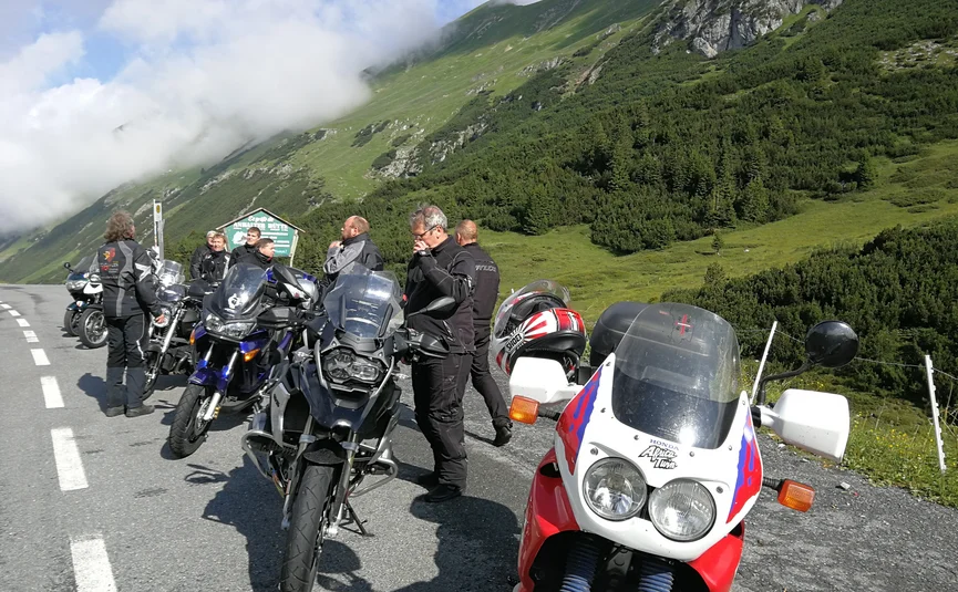 Motorrijders pauzeren op bergweg met groene heuvels en wolken