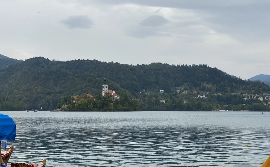 Kirche auf einer Insel in einem See mit bewaldeten Hügeln im Hintergrund