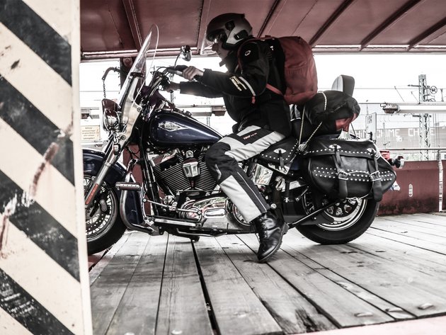 Motorrad- und Autoreisezug © Eduard Bopp Motorradfahrer mit Helm und Rucksack auf Harley Davidson Motorrad