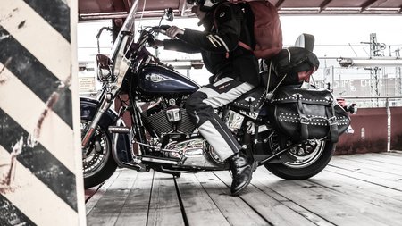 Motorrad- und Autoreisezug © Eduard Bopp Motorradfahrer mit Helm und Rucksack auf Harley Davidson Motorrad