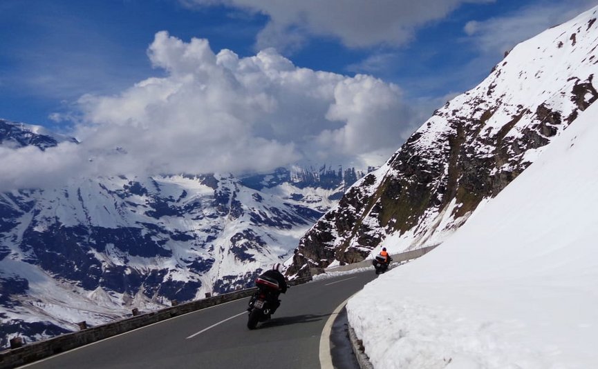 Sternfahrt Motorrad-Special ab € 628,- pro Person Motorradfahrer fahren auf einer kurvigen Bergstraße mit Schnee und Wolken