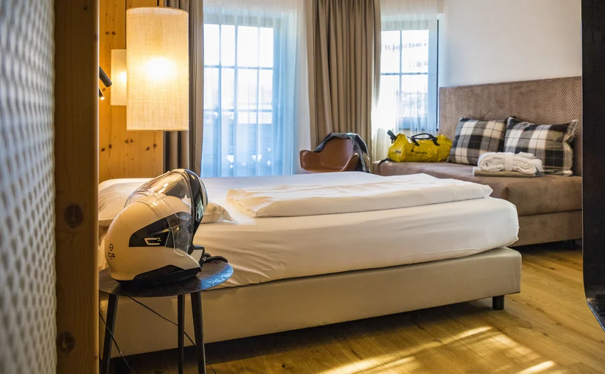 Cozy hotel room with single bed, chair, and motorcycle helmet on bedside table