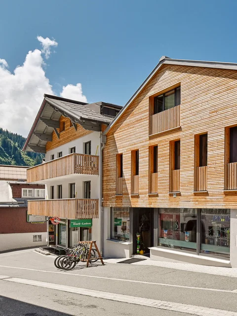 Street with modern wooden and stone houses under a blue sky