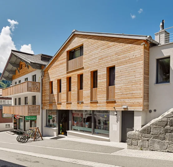 Straße mit modernen Häusern aus Holz und Stein unter blauem Himmel
