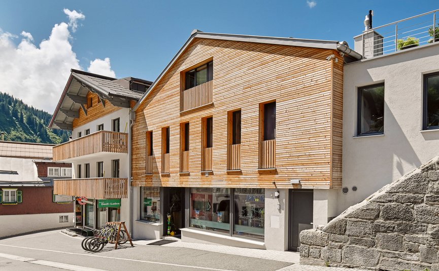Haus Flexen © Mathies Wilhelm Robert jun. Straße mit modernen Häusern aus Holz und Stein unter blauem Himmel