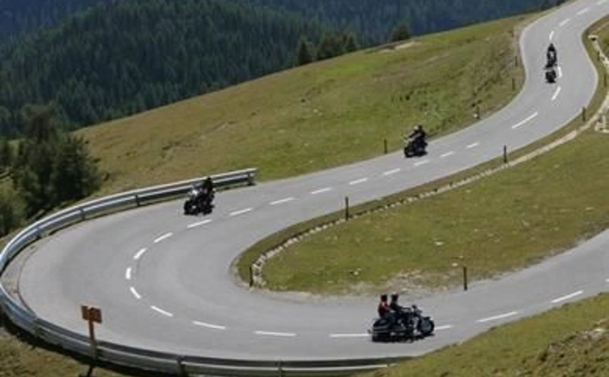 Motorradfahrer fahren eine kurvige Bergstraße hinauf