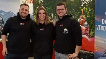 Drei Personen an einem Messestand für MoHo Motorrad Hotels