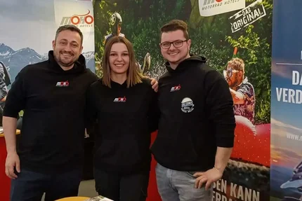 Three people at a booth for MoHo motorcycle hotels