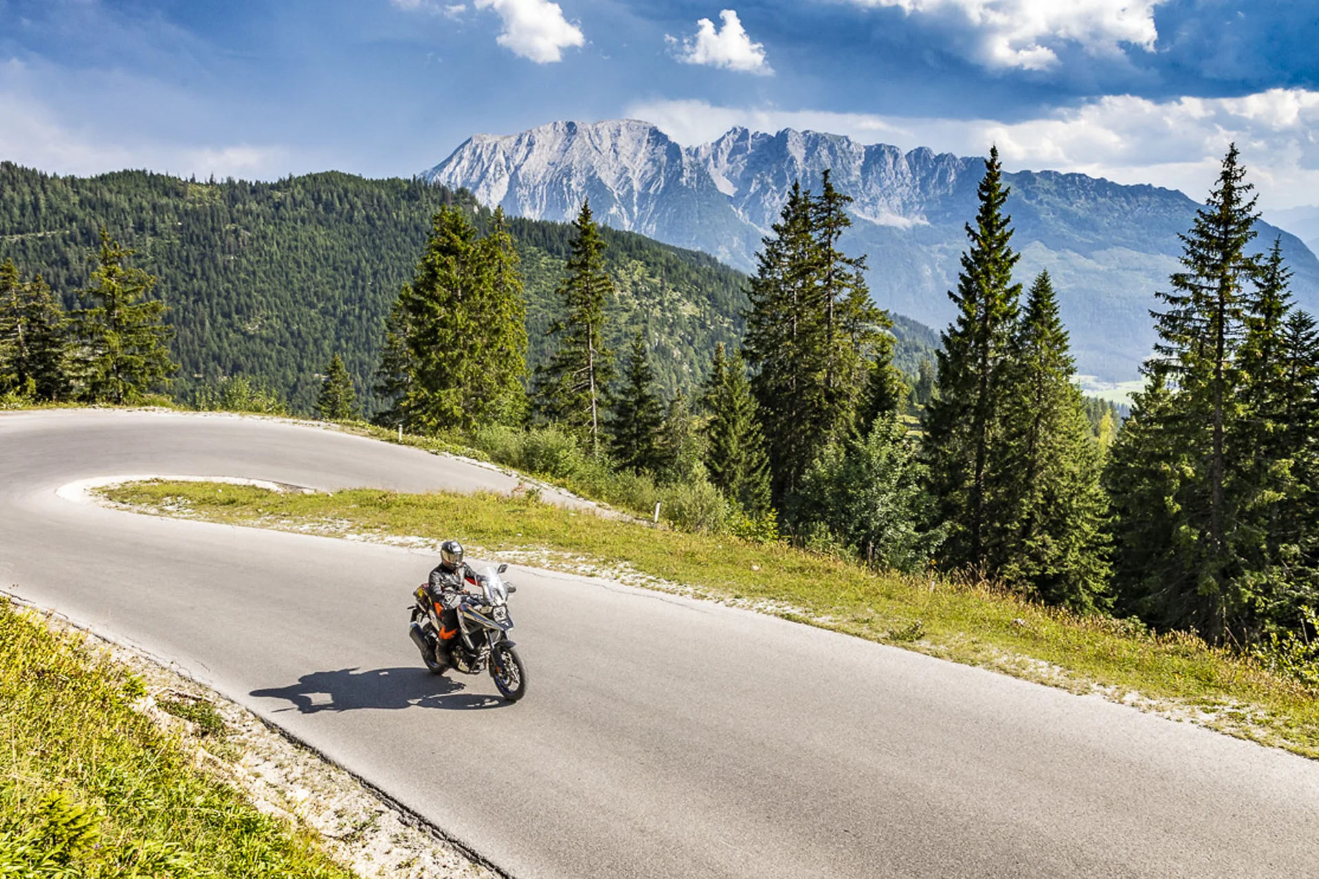 Motorbike holiday © Alexander Seger Motorcyclist on winding mountain road with pine trees and mountains behind