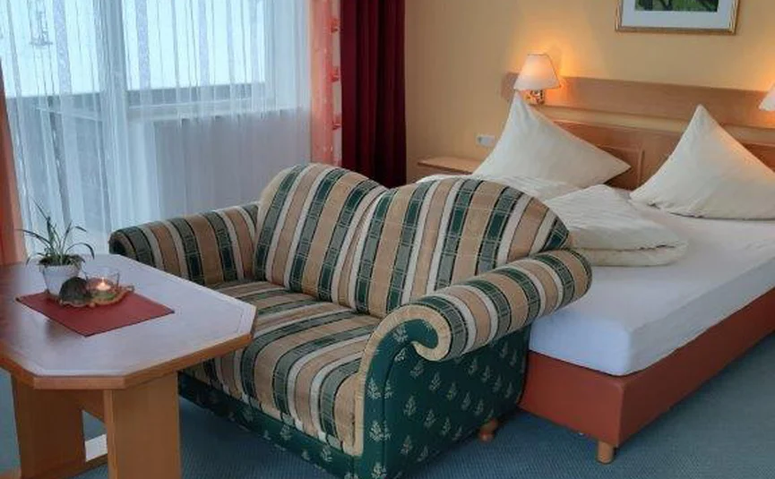 Hotel room with bed, sofa, table, and window with curtains