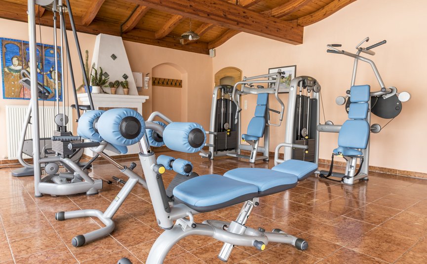 Fitnessraum mit blauen Trainingsgeräten und Holzbalkendecke