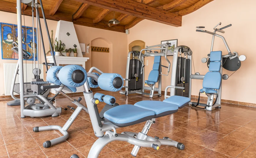 Fitnessruimte met blauwe fitnessapparatuur en houten balkenplafond