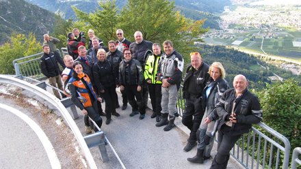 Gruppe von Motorradfahrern auf Bergstraße mit Talblick
