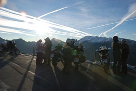 Motorradfahrer mit Motorrädern auf Bergstraße bei Sonnenuntergang und Bergen