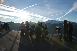 4 Touren Bike Woche Motorfietsers met motoren op bergweg bij zonsondergang met bergen op de achtergrond