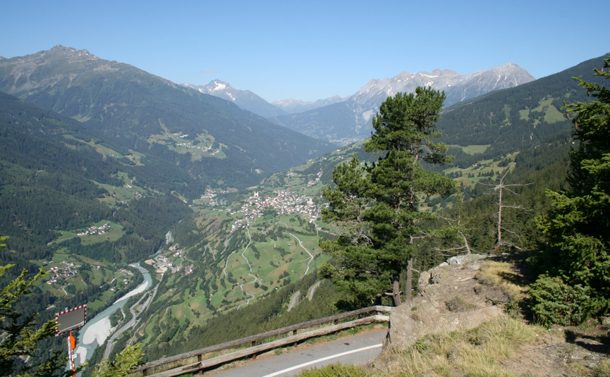 MoHo Schönauer Hof Tour Stelvio Variant 3 Livigno View of a valley with river, mountain villages, and forested mountains under clear sky