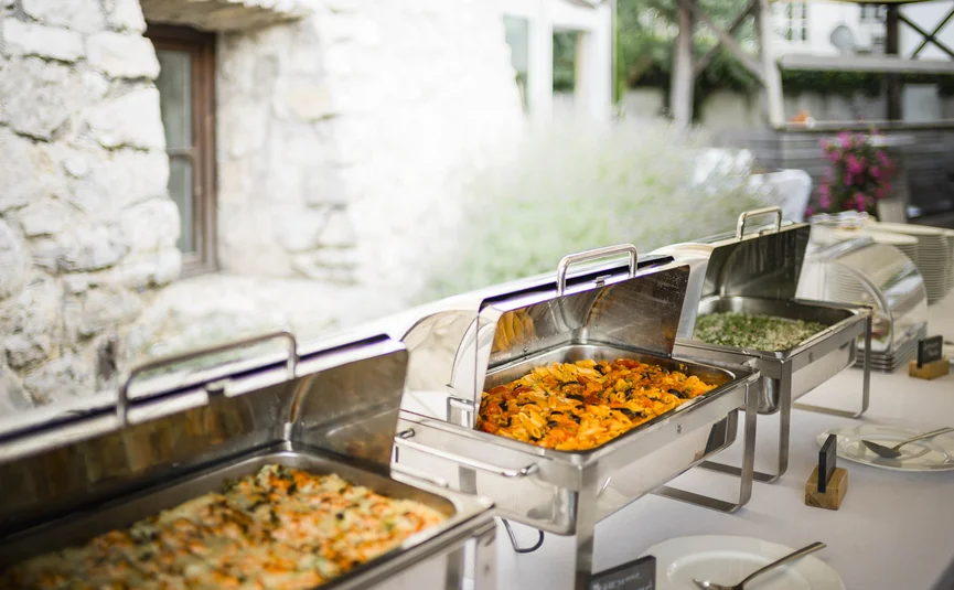 Buffet with hot dishes in stainless steel chafing dishes at event