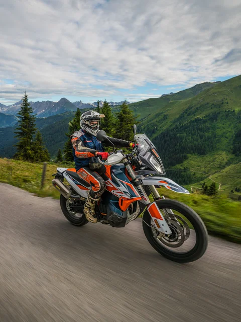 Two motorcyclists riding on a mountain road with alpine scenery