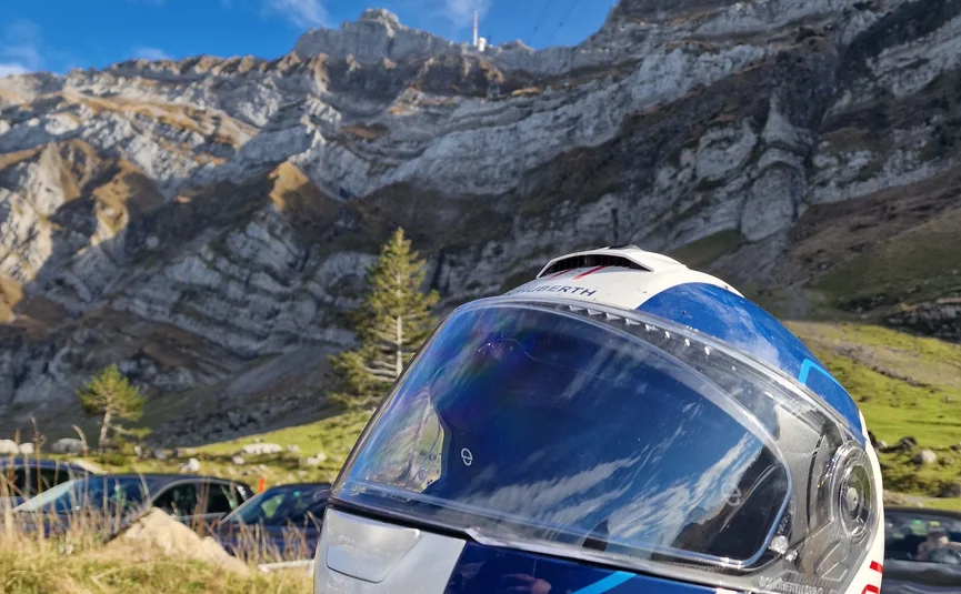 Motorcycle helmet with mountain landscape under blue sky and clouds