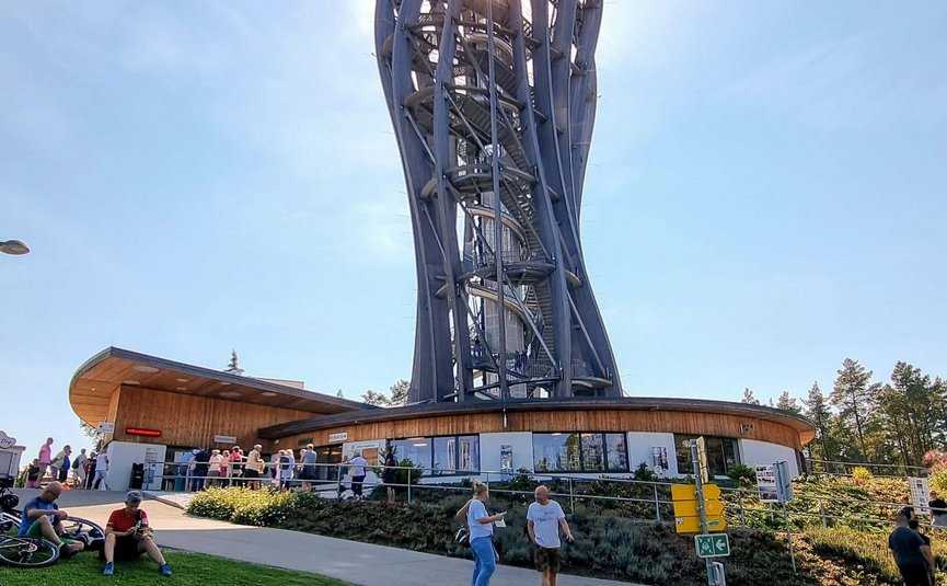 Moderne Aussichtsturm mit geschwungenem Design und Besuchern bei sonnigem Himmel