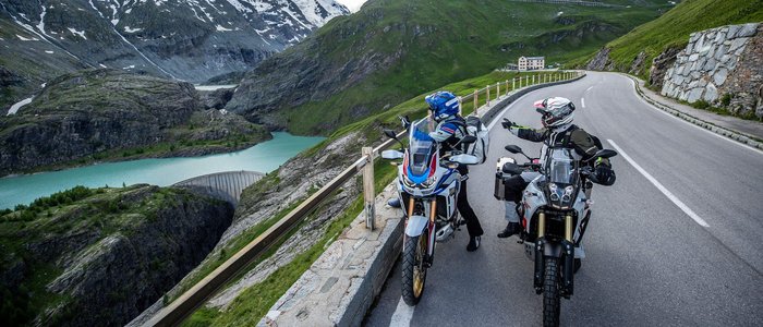 Großglockner – Hohe Tauern © Arturo Rivas Zwei Motorradfahrer auf Alpenstraße mit Bergsee und schneebedeckten Gipfeln